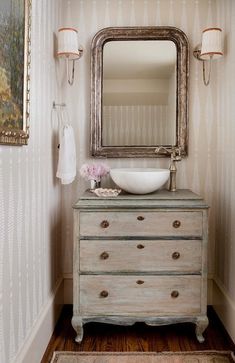 an old dresser with a sink and mirror in a room that has striped wallpaper on the walls