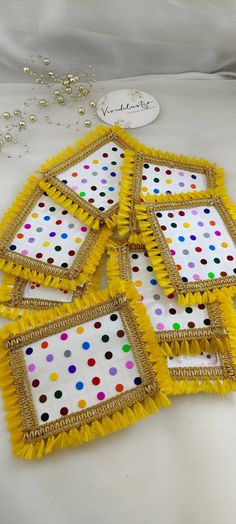 four yellow and white polka dot coasters with gold trimming on the edges, sitting next to a beaded necklace