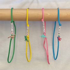 four different colored bracelets hanging from a wooden stick