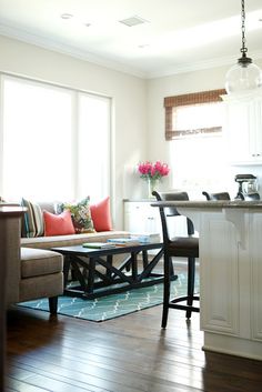 a living room filled with furniture next to a kitchen and breakfast nook area on top of a hard wood floor