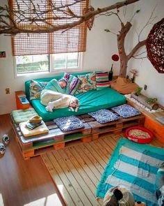 a living room filled with lots of furniture next to a wooden floor covered in pillows