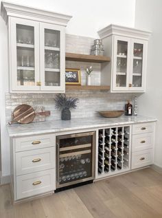 a kitchen with white cabinets and marble counter tops, wine rack in the center area