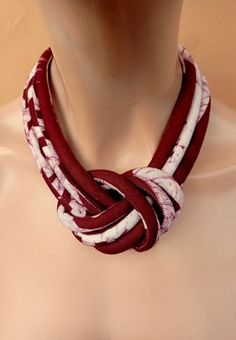 a woman wearing a red and white necklace on top of a mannequin's torso