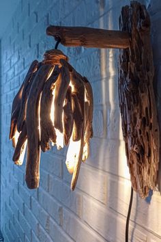 a light fixture made out of driftwood hanging from a brick wall