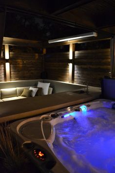 an indoor hot tub with blue lights on the side and couch in the back ground