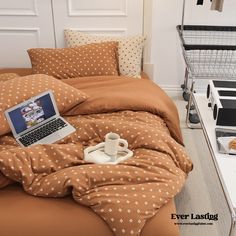 a laptop computer sitting on top of a bed covered in brown polka dot comforters