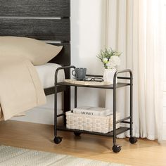 a bed sitting next to a night stand on top of a wooden floor