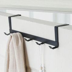 a towel is hanging on the wall next to a rack with two hooks and a white towel