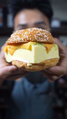 a person holding a sandwich with cheese and sauce on it