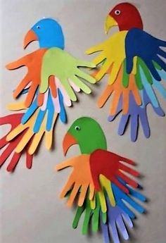 three colorful birds made out of paper sitting on top of a white table next to each other