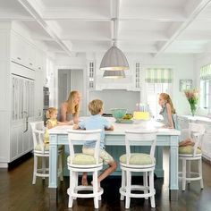 three children sitting at a kitchen table in front of an island with chairs around it