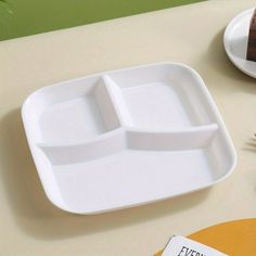 there is a white plate with two compartments on it and a brown cake in the background