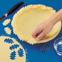 a person is decorating a pie with blue and yellow decorations on the table next to it