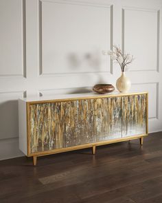 a white vase sitting on top of a wooden table next to a mirror covered cabinet