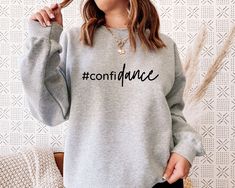 "Confidance Sweatshirt, Funny Dance Shirt, Dancer Gifts, Dance Teacher Gifts, Dance Teacher Hoodie, Dance Class Shirt, Dancing Gift Welcome to NIOBE BOUTIQUE. I am happy to see you in my shop. My main purpose is to meet you with a high-quality product. I use the best product to make you happy. Your satisfaction is my priority.  Placing an order is simple!  *Please review all images in this listing for style, color, and sizes.  *Select your t-shirt color and size from the drop-down menus.  *Choose your quantity as much as you need. *Please click the \"Proceed to Check Out\" button *Finally, your shirts will be ready to ship 1-3 Business Day. If you have any difficulties, send me a message. The size chart and color chart is ready in every listing. Please check these charts carefully before c Faith Tees, Dance Shirts, Fall Tee, Dance Teacher, Vinyl Shirts, New Year Wishes, Oversized Pullover, Mom Tees, Halloween Tees