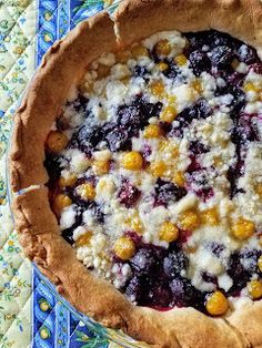 a pie with blueberries, oranges and other toppings in it on a table