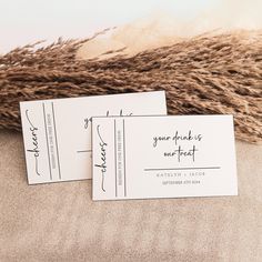 two white business cards sitting on top of a pile of brown furnishing next to each other