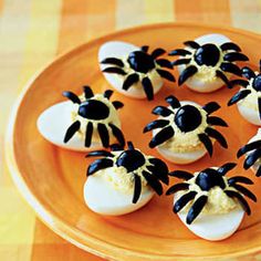 deviled eggs with black and white decorations on an orange tray, ready to be eaten