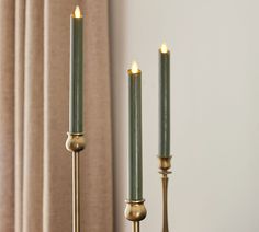 two candles are sitting next to each other in front of a window with drapes