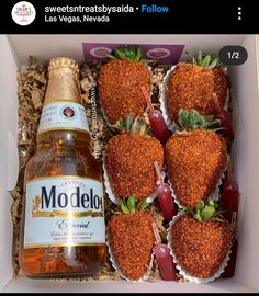 a box filled with strawberries next to a bottle of booze and some candy