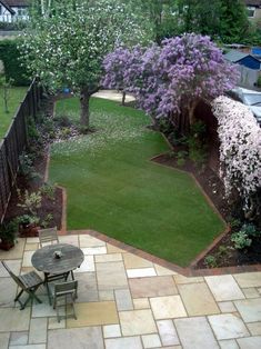 a backyard with a table and chairs next to a tree in the middle of it