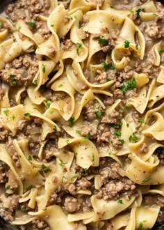 a skillet filled with pasta and ground beef in a creamy sauce, topped with parsley