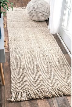 a white rug on the floor next to a window with a potted plant in it