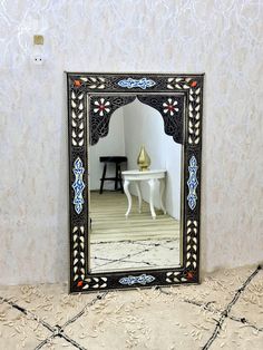 a mirror sitting on top of a tiled floor next to a white table and chair