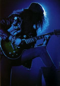 a man with long hair playing an electric guitar