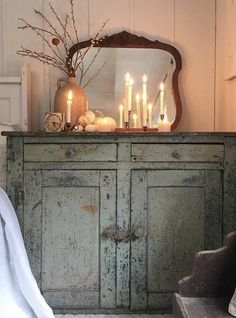 an old dresser with candles on it in front of a mirror