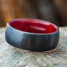 a red and black ring sitting on top of a rock