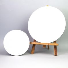 two white round objects sitting on top of wooden stands in front of a gray wall