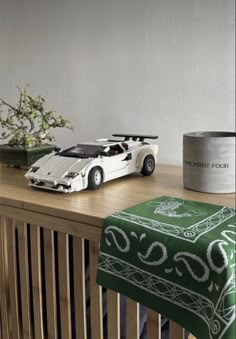 a toy car sitting on top of a wooden table next to a potted plant