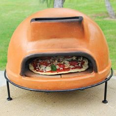 an outdoor pizza oven on top of a cement slab in front of a grassy area