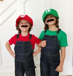 two children with fake moustaches on their faces standing next to each other