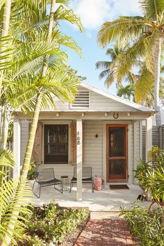 a small white house with palm trees in the front yard and red sign that says detent main