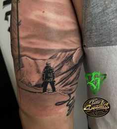 a man with a tattoo on his arm is standing in front of a mountain scene