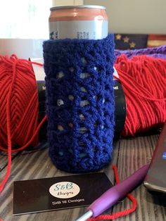 there is a cell phone, yarn and a can holder on the table next to it