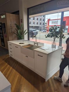 a man standing in front of a kitchen counter next to a window with a plant on it