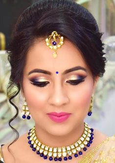 a woman in a bridal outfit with blue eyeshades and gold jewelry on her head