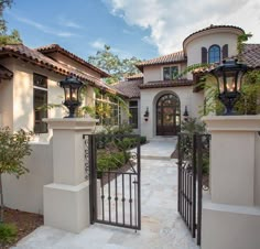 a gated entrance to a house with potted plants on the front and side