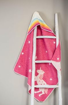 a pink towel hanging on the wall next to a ladder with stars and a unicorn on it