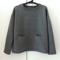 a gray sweater hanging on a white wall