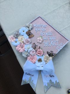 a graduation cap decorated with flowers and butterflies on top of a white tablecloth that says, wherever you go, go with all your heart