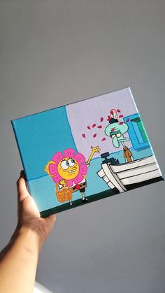 a hand holding up a cartoon book with an image of spongebob on it