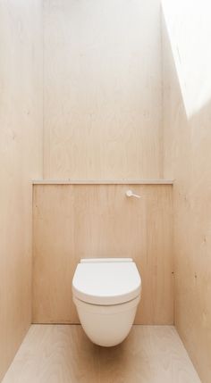 a white toilet sitting in the corner of a room with wood paneling on the walls