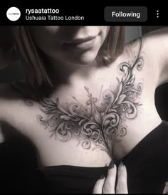 a woman with tattoos on her chest is looking at the camera and holding her hands behind her back