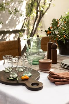 the table is set with glasses and pitchers on it, along with plates and utensils