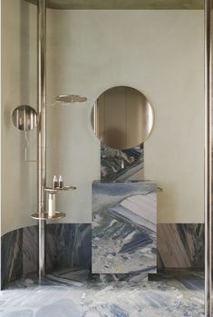 a bathroom with marble walls and flooring next to a round mirror on the wall