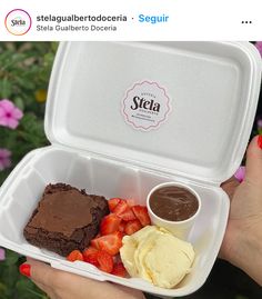 a person holding a plastic container filled with food and dipping sauces on top of strawberries